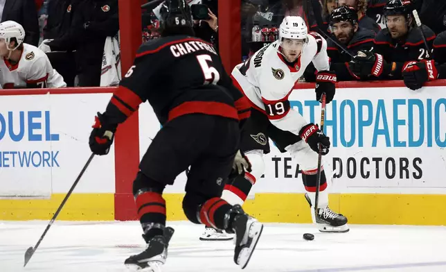 Ottawa Senators' Drake Batherson (19) controls the puck as he is approached by Carolina Hurricanes' Jalen Chatfield (5) during the first period of an NHL hockey game in Raleigh, N.C., Saturday, Nov. 16, 2024. (AP Photo/Karl B DeBlaker)