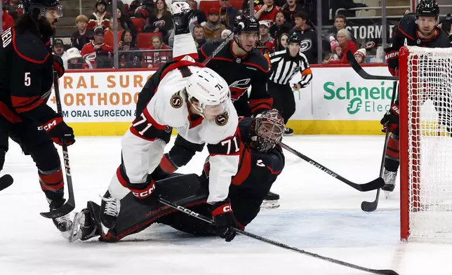 Ottawa Senators' Ridly Greig (71) collides with Carolina Hurricanes goaltender Spencer Martin (41) during the first period of an NHL hockey game in Raleigh, N.C., Saturday, Nov. 16, 2024. (AP Photo/Karl B DeBlaker)