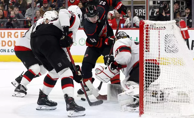 Carolina Hurricanes' Jackson Blake (53) battles for the puck with Ottawa Senators' Artem Zub, center, Nick Jensen, and goaltender Anton Forsberg (31) during the second period of an NHL hockey game in Raleigh, N.C., Saturday, Nov. 16, 2024. (AP Photo/Karl B DeBlaker)
