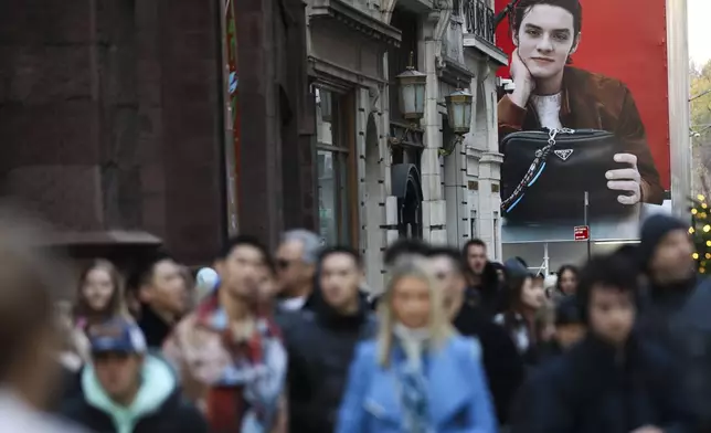 A large advertisement for Prada stands as shoppers walk along Fifth Avenue, Friday, Nov. 29, 2024, in New York. (AP Photo/Heather Khalifa)