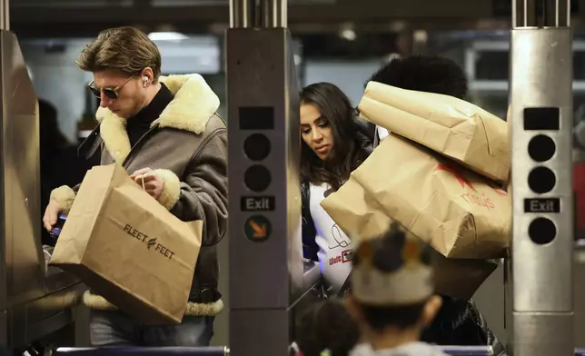 Shoppers manage their bags as they enter a Subway turnstile, Friday, Nov. 29, 2024, in New York. (AP Photo/Heather Khalifa)