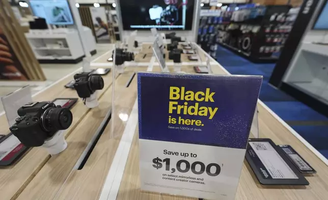 A sign promoting Black Friday deals sits on table with a display of mirrorless cameras in a Best Buy store Thursday, Nov. 21, 2024, in south Denver. (AP Photo/David Zalubowski)