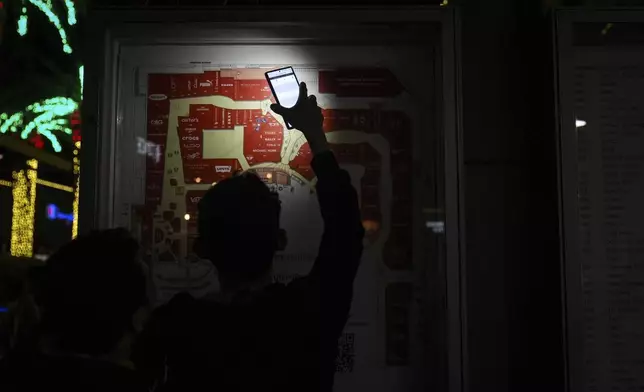 An early Black Friday shopper uses a smartphone flashlight to locate a store at Citadel Outlets in Commerce, Calif., Thursday, Nov. 28, 2024. (AP Photo/Jae C. Hong)