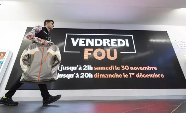 A Sport Expert's employee walks past a sign advertising Black Friday sales in Montreal on Friday, Nov. 29, 2024. (Christinne Muschi /The Canadian Press via AP)
