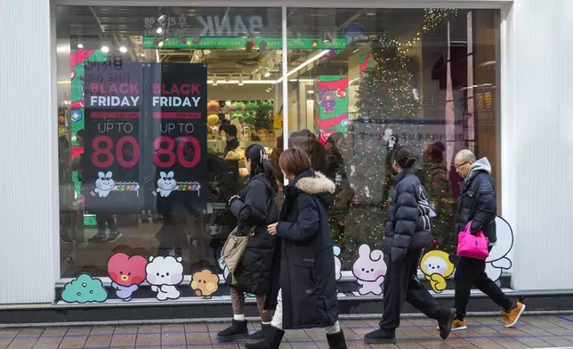 People walk by sale signs on the shopping street in Seoul, South Korea, Thursday, Nov. 28, 2024.(AP Photo/Ahn Young-joon)