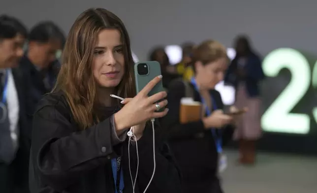 Activist Luisa Neubauer, of Germany, records on her phone at the COP29 U.N. Climate Summit, Thursday, Nov. 14, 2024, in Baku, Azerbaijan. (AP Photo/Peter Dejong)