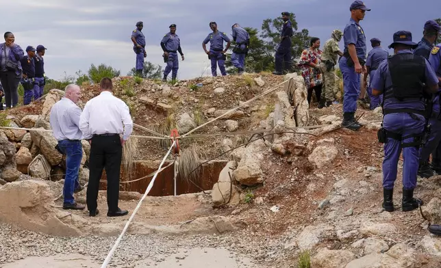 Police officers and private security personnel stand by the opening of a reformed gold mineshaft where illegal miners are trapped in Stilfontein, South Africa, Friday, Nov.15, 2024. (AP Photo/Denis Farrell)