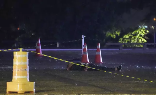 A body lies on a road outside the Supreme Court in Brasília, Brazil, following an explosion, Wednesday, Nov. 13, 2024. (AP Photo/Eraldo Peres)