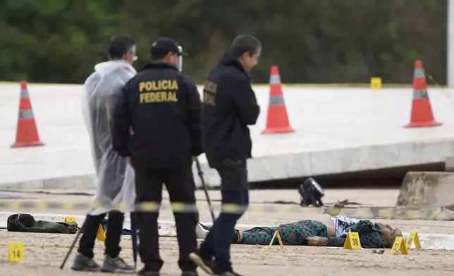 Federal police officers inspect a body outside the Supreme Court following an explosion the previous night, in Brasilia, Brazil, Thursday, Nov. 14, 2024. (AP Photo/Eraldo Peres)