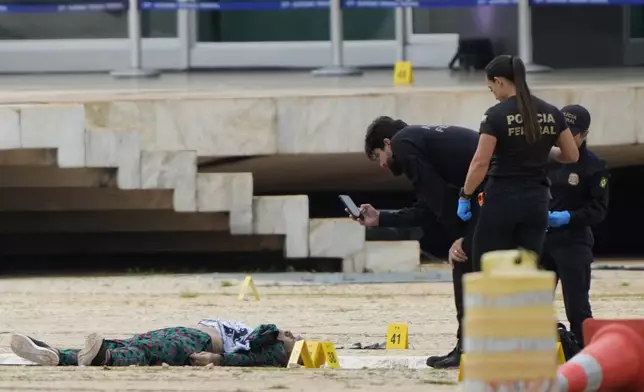 Federal police officers inspect a body outside the Supreme Court following an explosion the previous night, in Brasilia, Brazil, Thursday, Nov. 14, 2024. (AP Photo/Eraldo Peres)