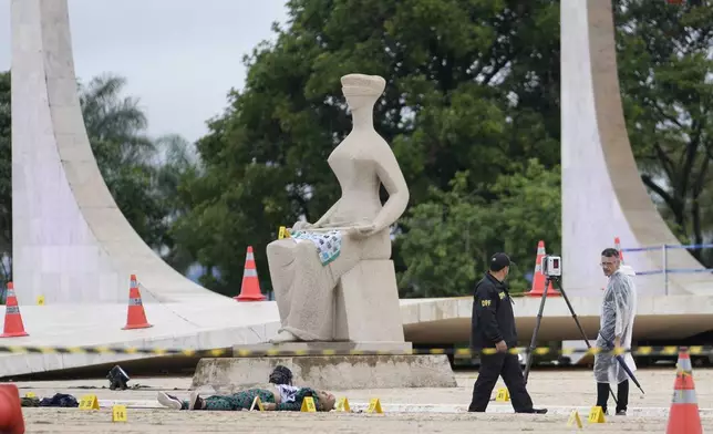 Federal police officers inspect a body outside the Supreme Court following an explosion the previous night, in Brasilia, Brazil, Thursday, Nov. 14, 2024. (AP Photo/Eraldo Peres)