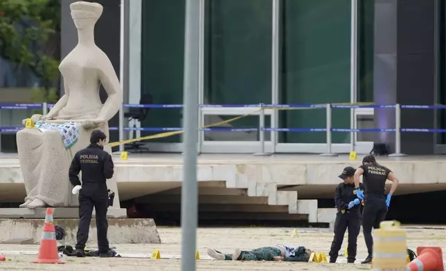 Federal police officers inspect a body outside the Supreme Court following an explosion the previous night, in Brasilia, Brazil, Thursday, Nov. 14, 2024. (AP Photo/Eraldo Peres)