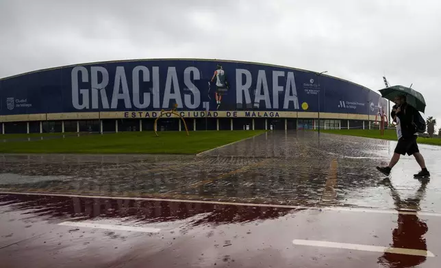 A man walks in front a banner reading in Spanish: "Thank you Rafa" during the Billie Jean King Cup finals at the Martin Carpena sportshall in Malaga, southern Spain, Wednesday, Nov. 13, 2024, after today's matches were canceled due to heavy rain and postponed until tomorrow. (AP Photo/Manu Fernandez)