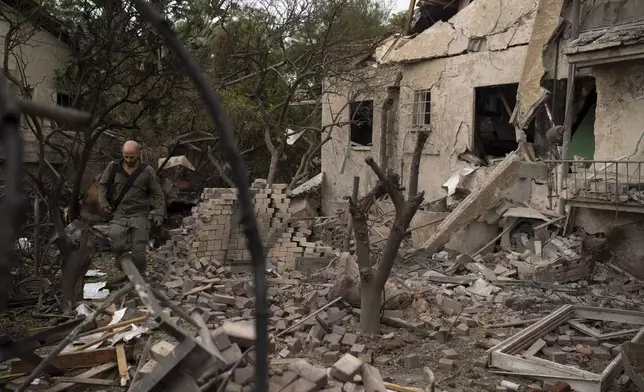 A member of the Israeli security forces inspects an impact site following a rocket fired from Lebanon hit an area in Rinatya, outskirts of Tel Aviv, Israel, Sunday, Nov. 24, 2024. (AP Photo/Leo Correa)