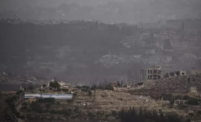 An Israeli flag stands next to destroyed buildings on an area in southern Lebanon as seen from northern Israel, Monday, Nov. 25, 2024. (AP Photo/Leo Correa)