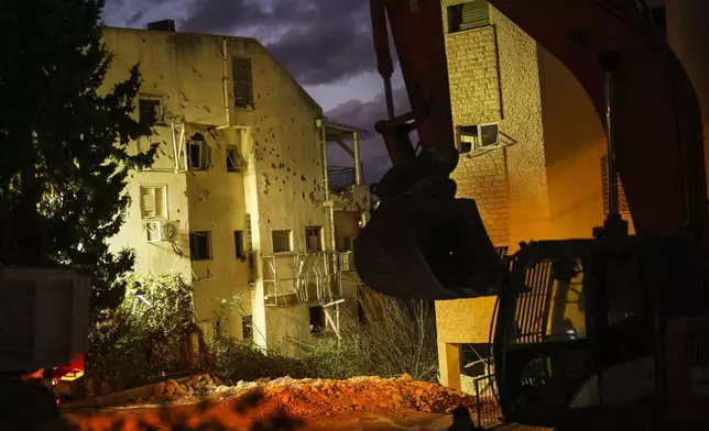 An excavator works at the site where a day before a residential building was hit by a rocket fired from Lebanon, in Haifa, Israel, Monday, Nov. 25, 2024. (AP Photo/Francisco Seco)