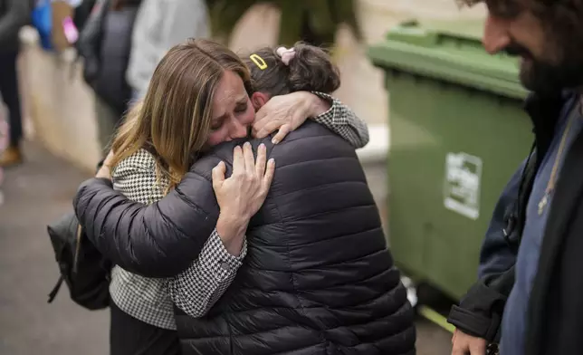 Local residents gather to collect their belongings the day after an apartment building was hit by a rocket fired from Lebanon, in Haifa, Israel, Monday, Nov. 25, 2024. (AP Photo/Francisco Seco)