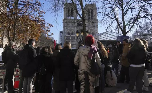 Tourists watch Notre-Dame cathedral from behind a security perimeter, Thursday, Nov. 28, 2024 in Paris. (AP Photo/Michel Euler)