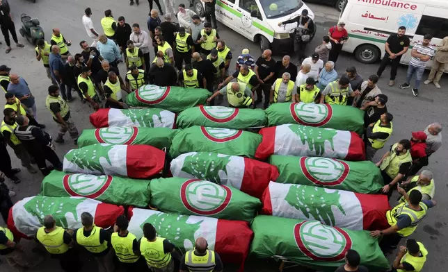 FILE - Paramedics stand next to the coffins of people who were killed in an Israeli airstrike in Barja, during their funeral procession in Tyre, southern Lebanon, on Nov. 7, 2024. (AP Photo/Mohammed Zaatari, File)