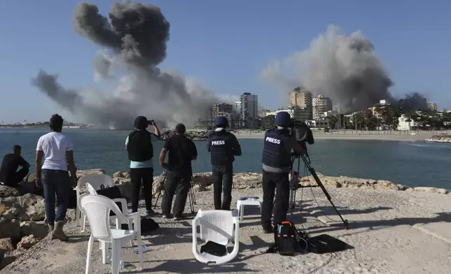 FILE - Journalists film as smoke rises from buildings hit in Israeli airstrikes in Tyre, southern Lebanon, on Oct. 28, 2024. (AP Photo/Mohammed Zaatari, File)