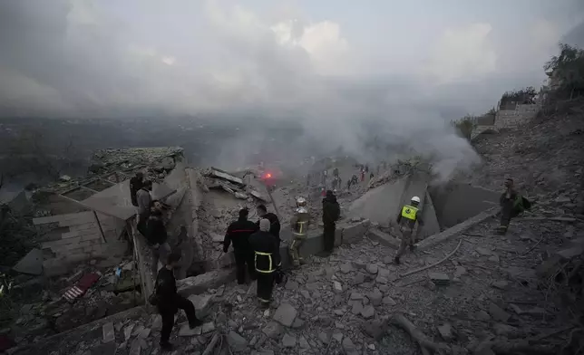 FILE - Rescue workers and people gather on the rubble of a house hit in an Israeli airstrike in Baalchmay village east of Beirut, Lebanon, on Nov. 12, 2024. (AP Photo/Hassan Ammar, File)