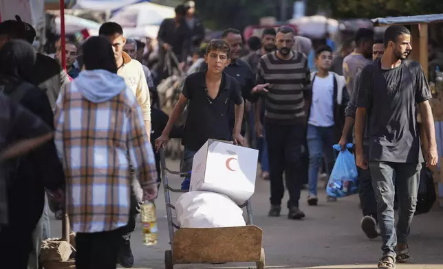 A Palestinian youth carries humanitarian aid in Deir al-Balah, Gaza, Wednesday, Nov. 13, 2024. (AP Photo/Abdel Kareem Hana)