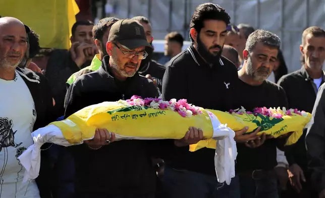 Mourners carry the bodies of two kids, killed on Monday evening in an Israeli airstrike, during a mass funeral in Saksakiyeh village, south Lebanon, Wednesday, Nov. 13, 2024.(AP Photo/Mohammed Zaatari)