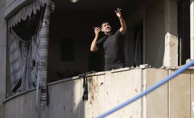 A resident gestures as he speaks on his mobile phone while checking his apartment at the site of an Israeli airstrike in Aramoun village, southeast of Beirut, Lebanon, Wednesday, Nov. 13, 2024. (AP Photo/Hassan Ammar)