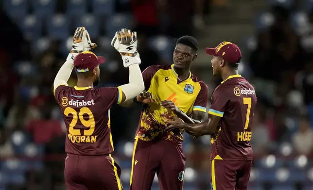 West Indies' Alzarri Joseph, center, celebrates with teammates Nicholas Pooran and Akeal Hosein the dismissal of England's captain Jos Buttler during the third T20 cricket match at Daren Sammy National Cricket Stadium in Gros Islet, St. Lucia, Thursday, Nov. 14, 2024. (AP Photo/Ricardo Mazalan)