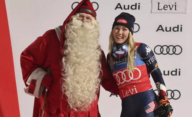 The winner United States' Mikaela Shiffrin celebrates on podium with Santa, after an alpine ski, women's World Cup slalom, in Levi, Finland, Saturday, Nov. 16, 2024. (AP Photo/Marco Trovati)