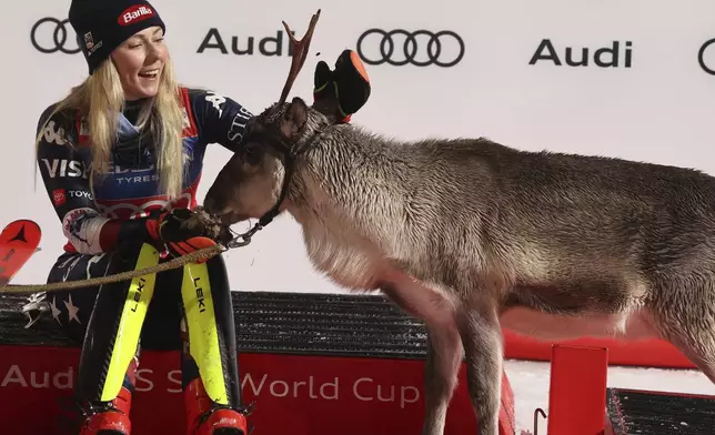 The winner United States' Mikaela Shiffrin makes friends with a baby reindeer as she waits for Santa on podium after an alpine ski, women's World Cup slalom, in Levi, Finland, Saturday, Nov. 16, 2024. (AP Photo/Marco Trovati)