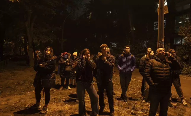 Local residents look up at the fire in a residential building after an attack of Russian drones in Kyiv, Ukraine, Friday, Oct. 26, 2024. (AP Photo/Alex Babenko)