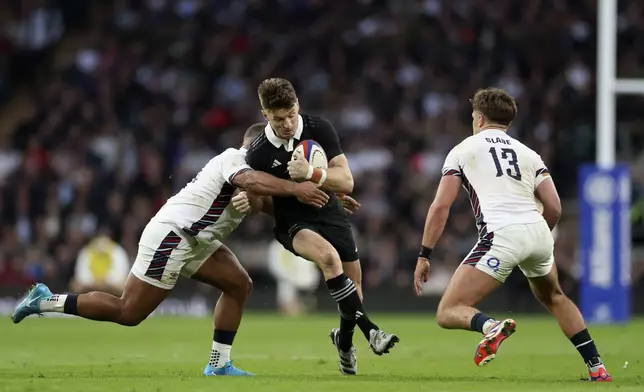 New Zealand's Jordie Barrett, centre, is tackled by England's Ollie Lawrence, left, during the Autumn Nations Series rugby match between England and New Zealand, at Twickenham stadium, in London Saturday, Nov. 2, 2024. (AP Photo/Ian Walton)