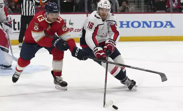 Florida Panthers center Sam Reinhart (13) and Washington Capitals right wing Taylor Raddysh (16) go for the puck during the second period of an NHL hockey game, Monday, Nov. 25, 2024, in Sunrise, Fla. (AP Photo/Lynne Sladky)