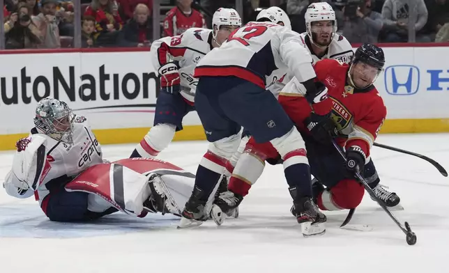 Washington Capitals goaltender Logan Thompson, left, watches as Florida Panthers defenseman Dmitry Kulikov, right, goes for the puck during the second period of an NHL hockey game, Monday, Nov. 25, 2024, in Sunrise, Fla. (AP Photo/Lynne Sladky)