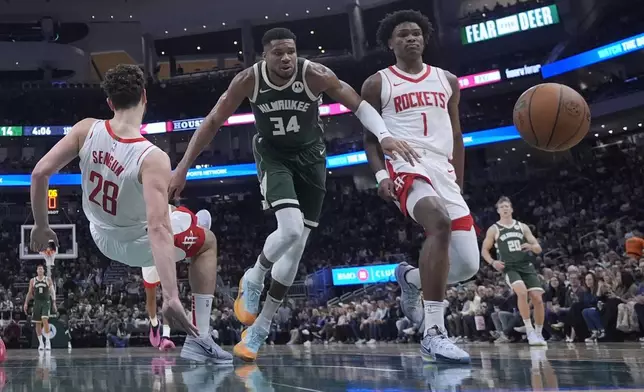 Milwaukee Bucks' Giannis Antetokounmpo goes after a loose ball with Houston Rockets' Alperen Sengun and Amen Thompson during the first half of an NBA basketball game Monday, Nov. 18, 2024, in Milwaukee. The Bucks won 101-100. (AP Photo/Morry Gash)