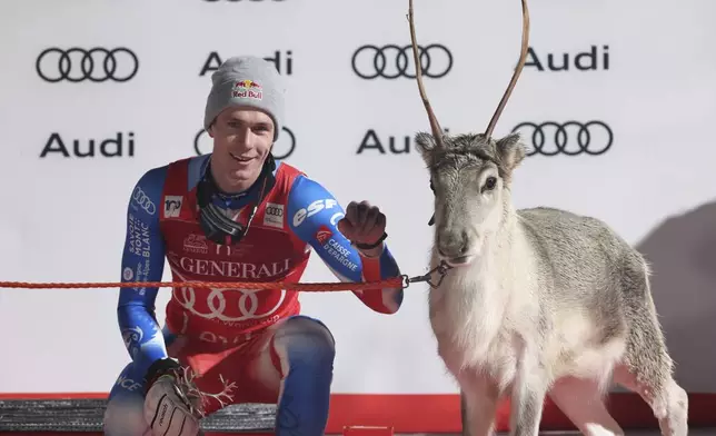 The winner France's Clement Noel celebrates on podium with a young reindeer after an alpine ski, men's World Cup slalom, in Levi, Finland, Sunday, Nov. 17, 2024. (AP Photo/Marco Trovati)