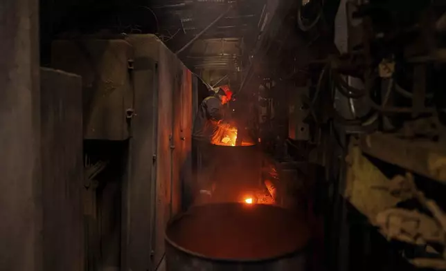 A worker throws firewood into a stove to heat pipes at DTEK's power plant after a recent Russian missile attack in Ukraine, Nov. 28, 2024. (AP Photo/Evgeniy Maloletka)