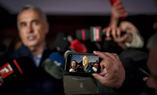 A journalist records Calin Georgescu, running as an independent candidate for president gestures while delivering a speech to media, in Izvorani, Romania, Tuesday, Nov. 26, 2024, after making it to the Dec. 8 election runoff. (AP Photo/Vadim Ghirda)