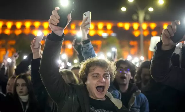 Youngsters shout slogans and flash the light of their mobile phones in Bucharest, Romania, Wednesday, Nov. 27, 2024, during a protest against Calin Georgescu, the independent candidate for Romanian presidency who won the first round of elections making it to the Dec. 8, runoff. (AP Photo/Vadim Ghirda)