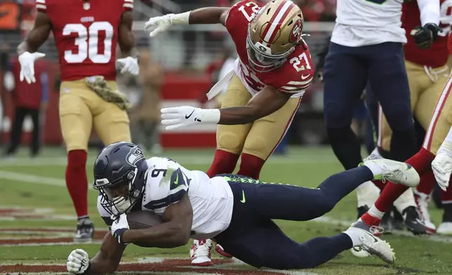 Seattle Seahawks running back Kenneth Walker III (9) scores a touchdown past San Francisco 49ers safety Ji'Ayir Brown (27) during the second half of an NFL football game in Santa Clara, Calif., Sunday, Nov. 17, 2024. (AP Photo/Jed Jacobsohn)