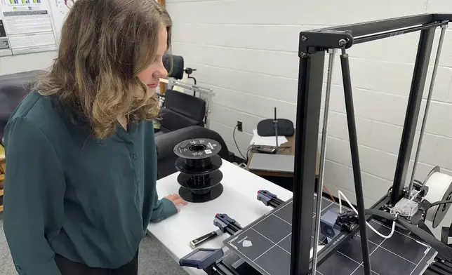 Rylie DuBois, a sophomore biosystems engineering major at Michigan State University, watches as a 3D printer creates helmet inserts at the school's Biomechanical Design Research Laboratory, Monday, Nov. 18, 2024, in East Lansing, Mich. (AP Photo/Mike Householder)