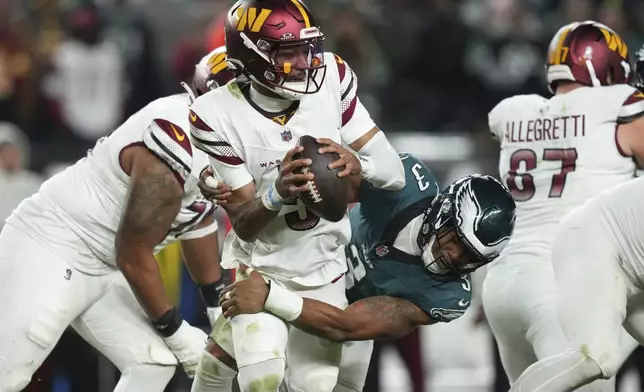 Washington Commanders quarterback Jayden Daniels (5) is sacked by Philadelphia Eagles linebacker Nolan Smith Jr. (3) during the second half of an NFL football game Thursday, Nov. 14, 2024, in Philadelphia. (AP Photo/Matt Slocum)