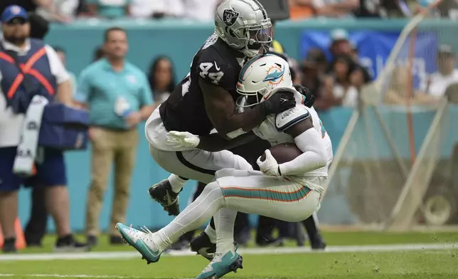 Las Vegas Raiders defensive end K'Lavon Chaisson (44) tackles Miami Dolphins running back De'Von Achane (28) during the second half of an NFL football game, Sunday, Nov. 17, 2024, in Miami Gardens, Fla. (AP Photo/Rebecca Blackwell)