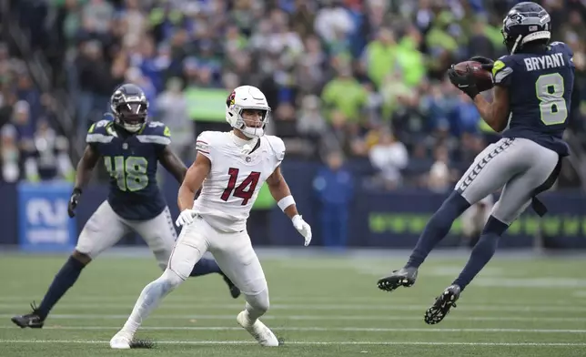 Arizona Cardinals wide receiver Michael Wilson (14) watches at Seattle Seahawks cornerback Coby Bryant (8) as he makes an interception during the second half of an NFL football game Sunday, Nov. 24, 2024, in Seattle. Bryant ran the ball in for a touchdown on the play. (AP Photo/Jason Redmond)