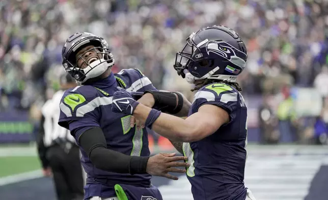 Seattle Seahawks quarterback Geno Smith (7) celebrates with Seattle Seahawks wide receiver Jaxon Smith-Njigba, right, after Smith threw to Smith-Njigba for a touchdown during the first half of an NFL football game against the Arizona Cardinals, Sunday, Nov. 24, 2024, in Seattle. (AP Photo/Stephen Brashear)