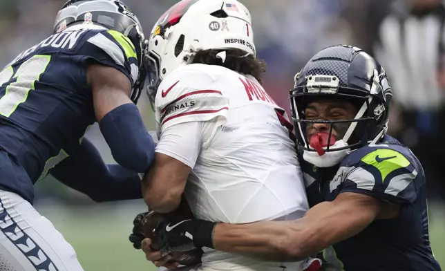 Seattle Seahawks cornerback Devon Witherspoon, left, and cornerback Coby Bryant, right, tackle Arizona Cardinals quarterback Kyler Murray during the first half of an NFL football game Sunday, Nov. 24, 2024, in Seattle. (AP Photo/Jason Redmond)