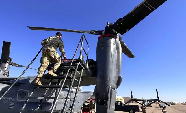 Master Sgt. Frank Williams, the production superintendent of the 20th Special Operations aircraft maintenance squadron at Cannon Air Force Base, N.M., climbs a ladder to show where hydraulic lines at the joint of the rotating engine and transmission need to be checked on the Osprey after flights, Oct. 8, 2024. (AP Photo/Tara Copp)