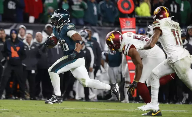 Philadelphia Eagles running back Saquon Barkley, left, runs for a touchdown during the second half of an NFL football game against the Washington Commanders Thursday, Nov. 14, 2024, in Philadelphia. (AP Photo/Laurence Kesterson)