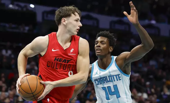 Miami Heat guard Pelle Larsson, left, looks to pass the ball against Charlotte Hornets forward Moussa Diabate during the first half of an NBA basketball game in Charlotte, N.C., Wednesday, Nov. 27, 2024. (AP Photo/Nell Redmond)